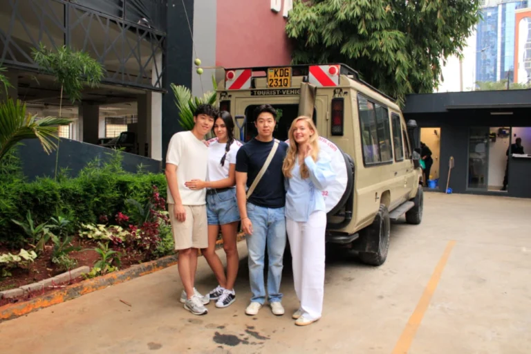Three guests standing beside a Kibokoni safari vehicle before departure