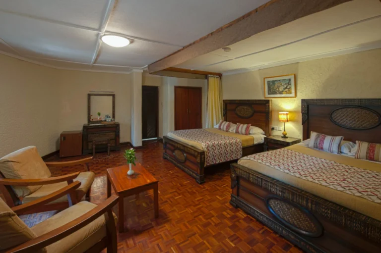 Twin beds and wooden furnishings in a guest room at Masai Mara Sopa Lodge