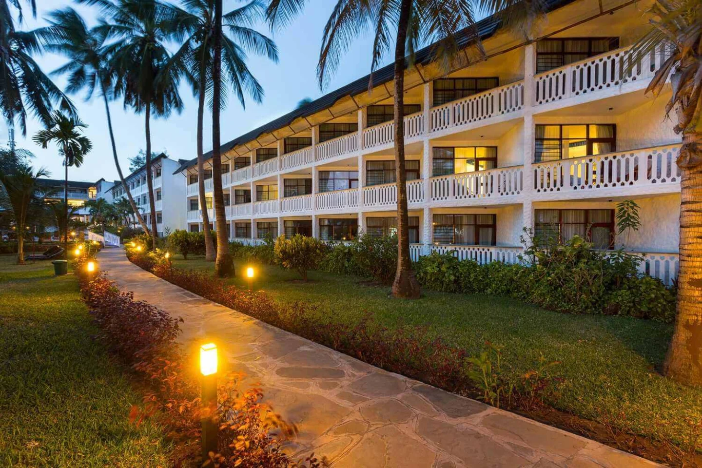 Palm-lined path beside guest-room balconies at Travellers Beach Hotel & Club