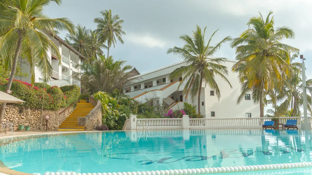 Swimming pool with palm trees and white resort buildings at Voyager Beach Resort